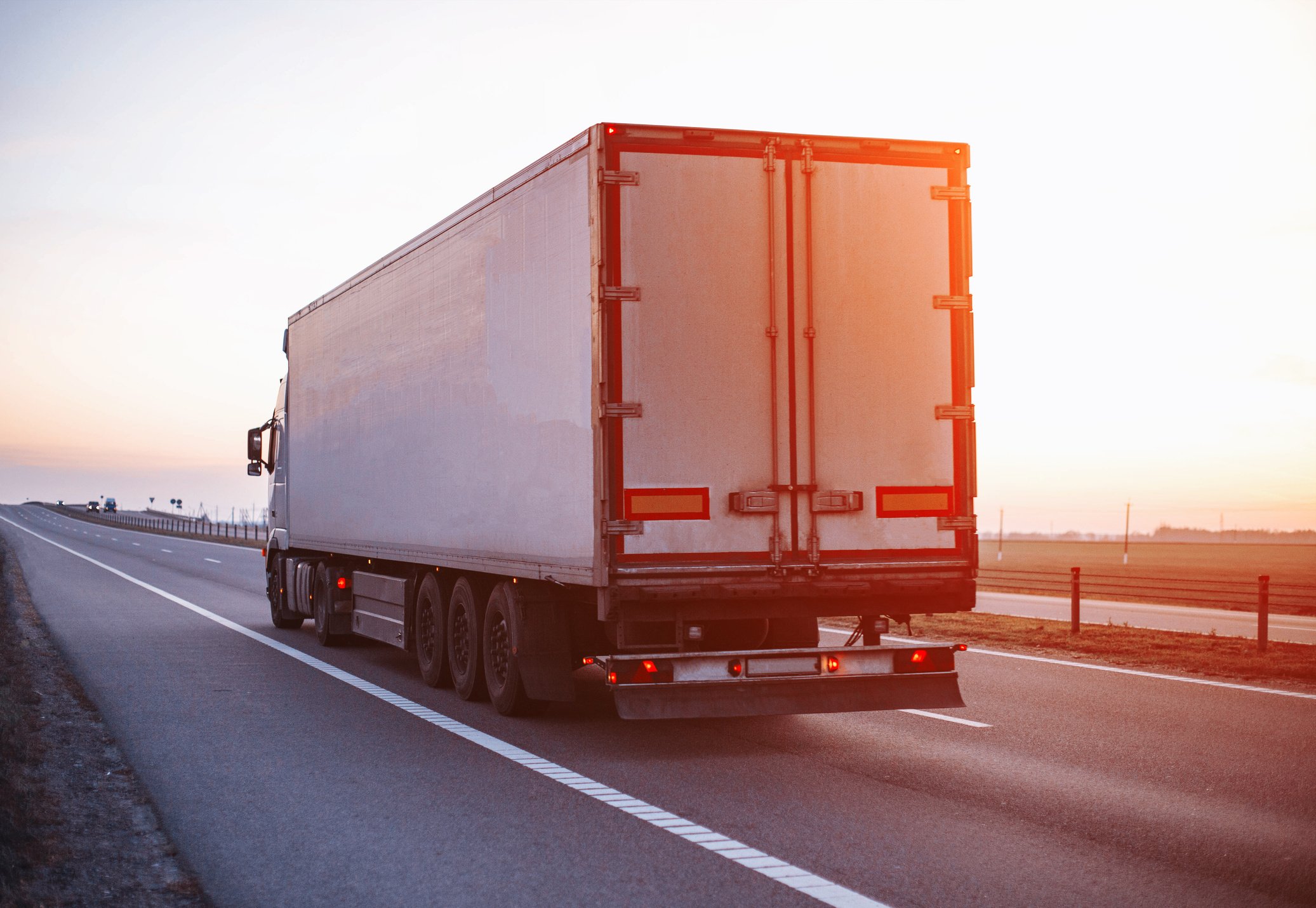 A Truck with a Trailer Carries a Groupage Cargo on the Highway against the Backdrop of Sunset. Concept of Classification of Transported Goods, Logistics, Cargo Handling